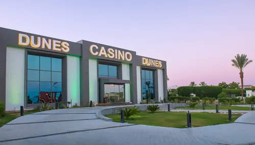 The lit entrance of Dunes Casino at dusk